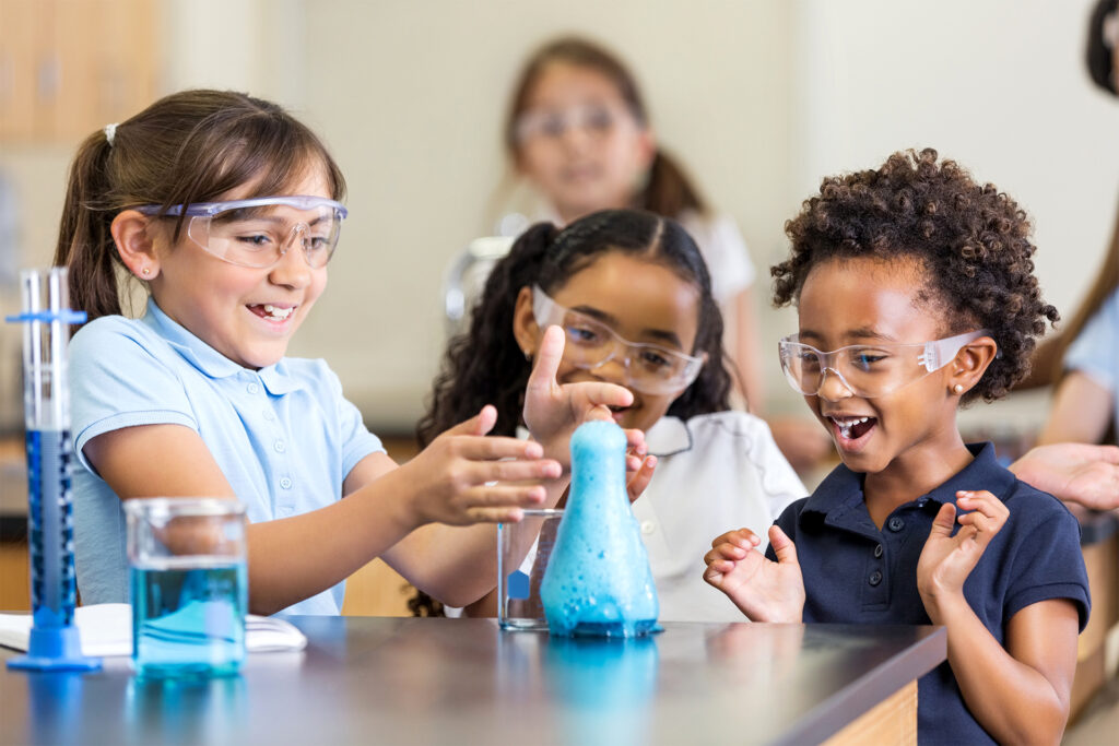 Excited girls using chemistry set together in elementary science classroom